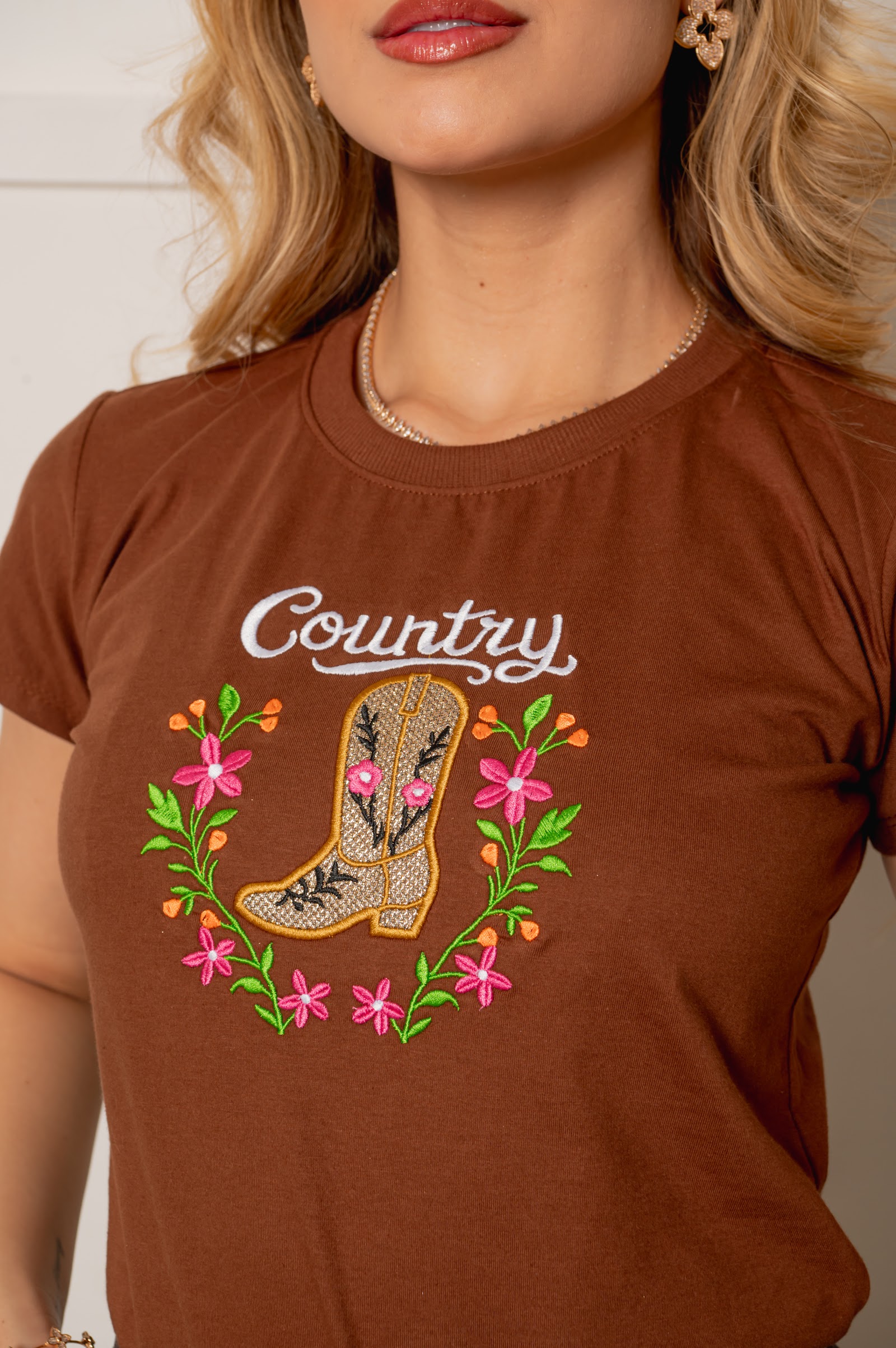 Detalhe do bordado de bota e flores na T-shirt terracota