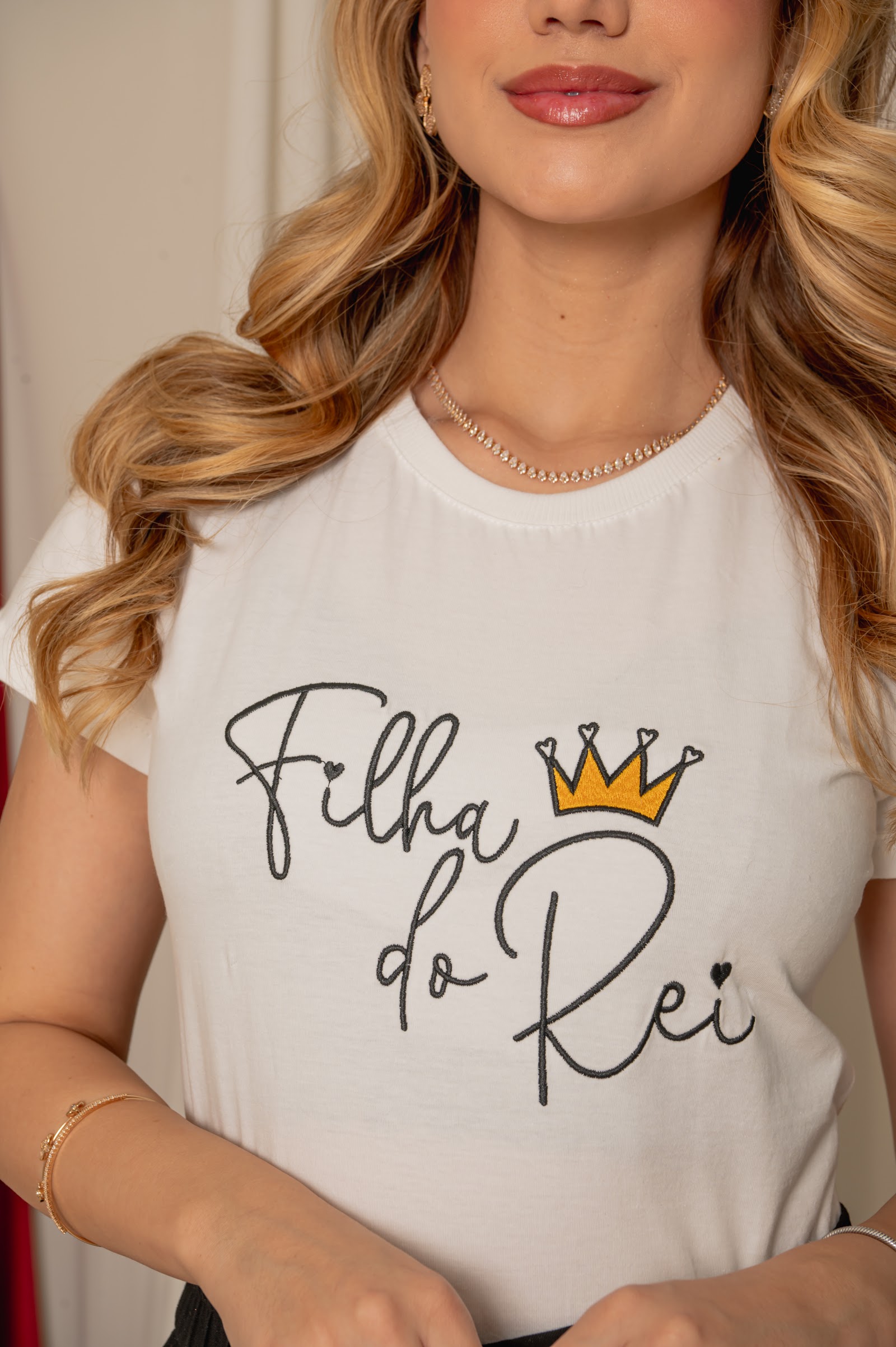 Detalhe da mensagem Filha do Rei e coroa na T-shirt branca